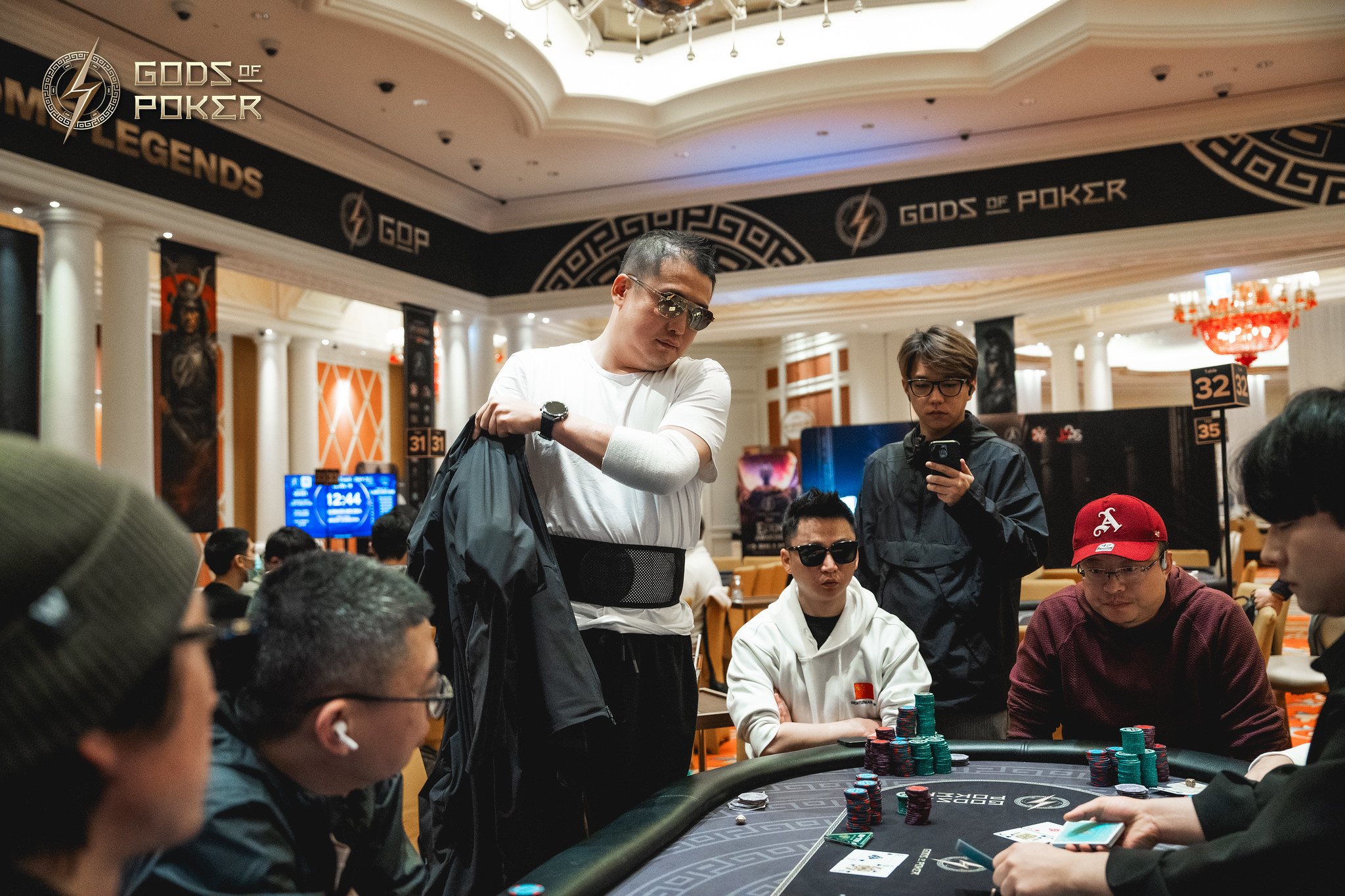 Men playing poker at a casino table during a 'Gods of Poker' event.