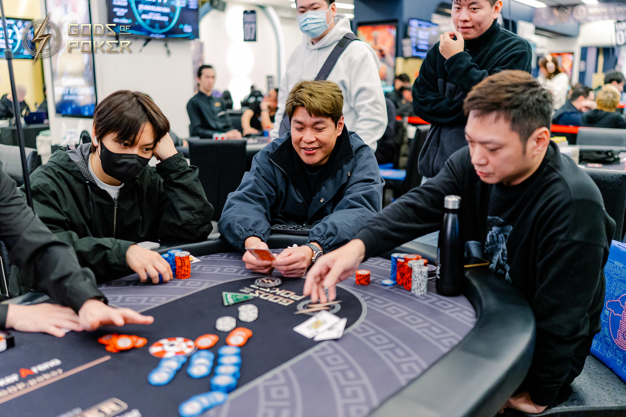 Poker players engaged in a game around a table with cards and chips.