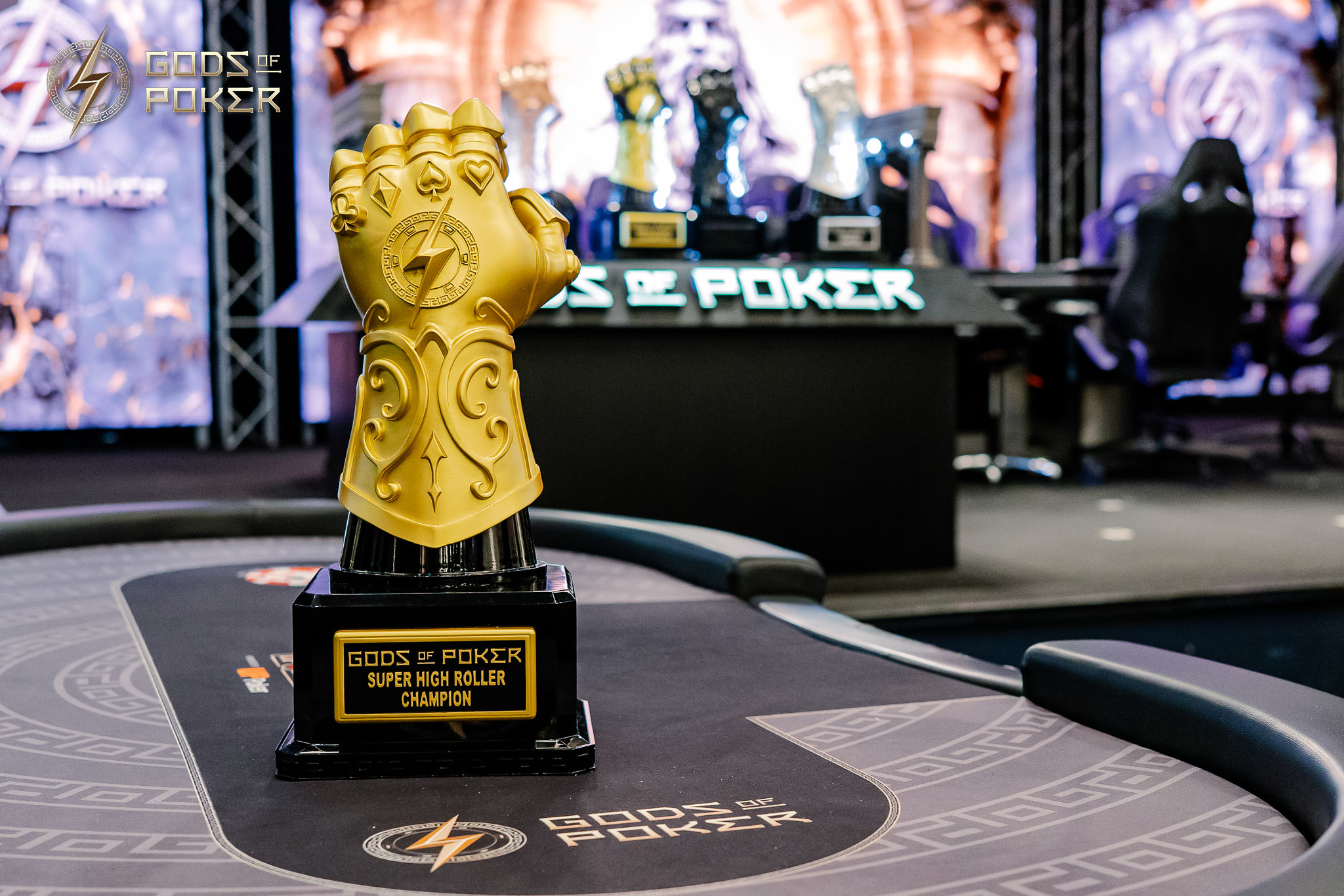 Golden Infinity Gauntlet trophy on a poker table with 'GODS OF POKER' inscribed.
