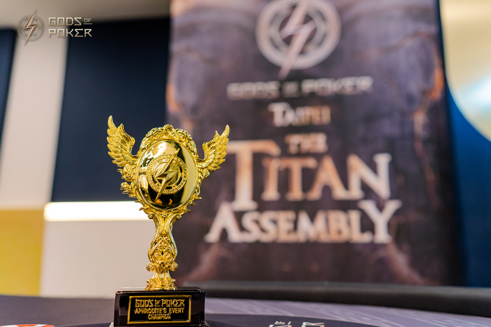 Golden trophy with a winged figure, in front of a banner for 'The Titan Assembly'.