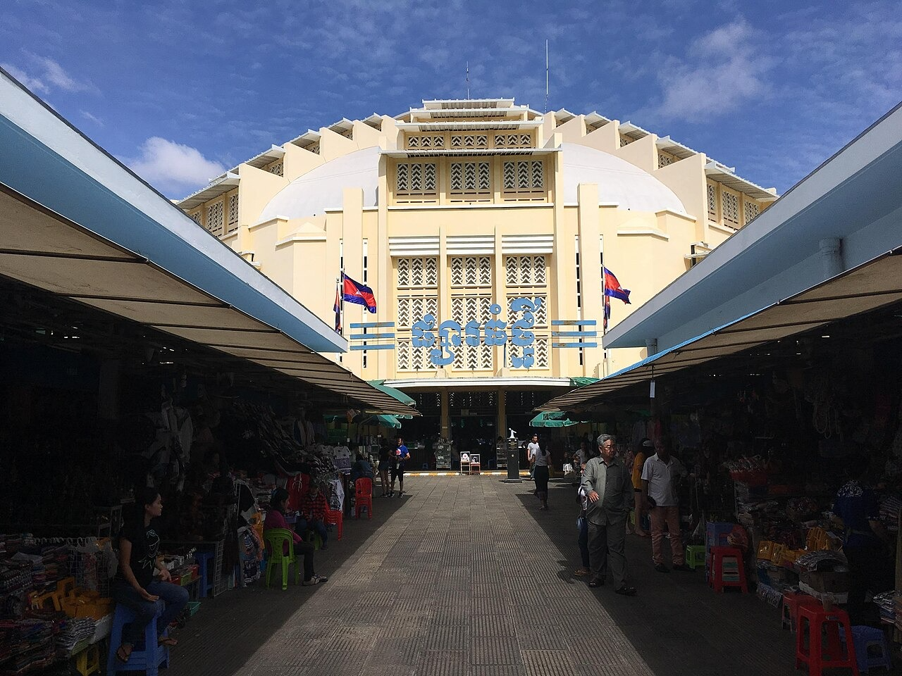 Ornate yellow domed market building in Phnom Penh, Cambodia, with vendors and shoppers.
