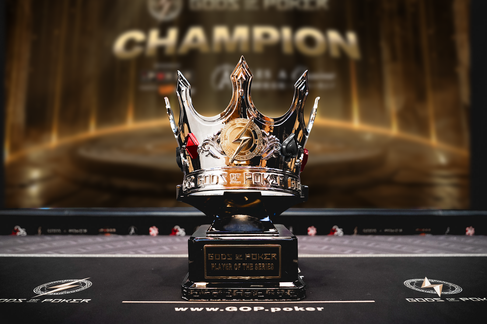 Ornate silver and gold Gods of Poker champion crown trophy on a dark table.