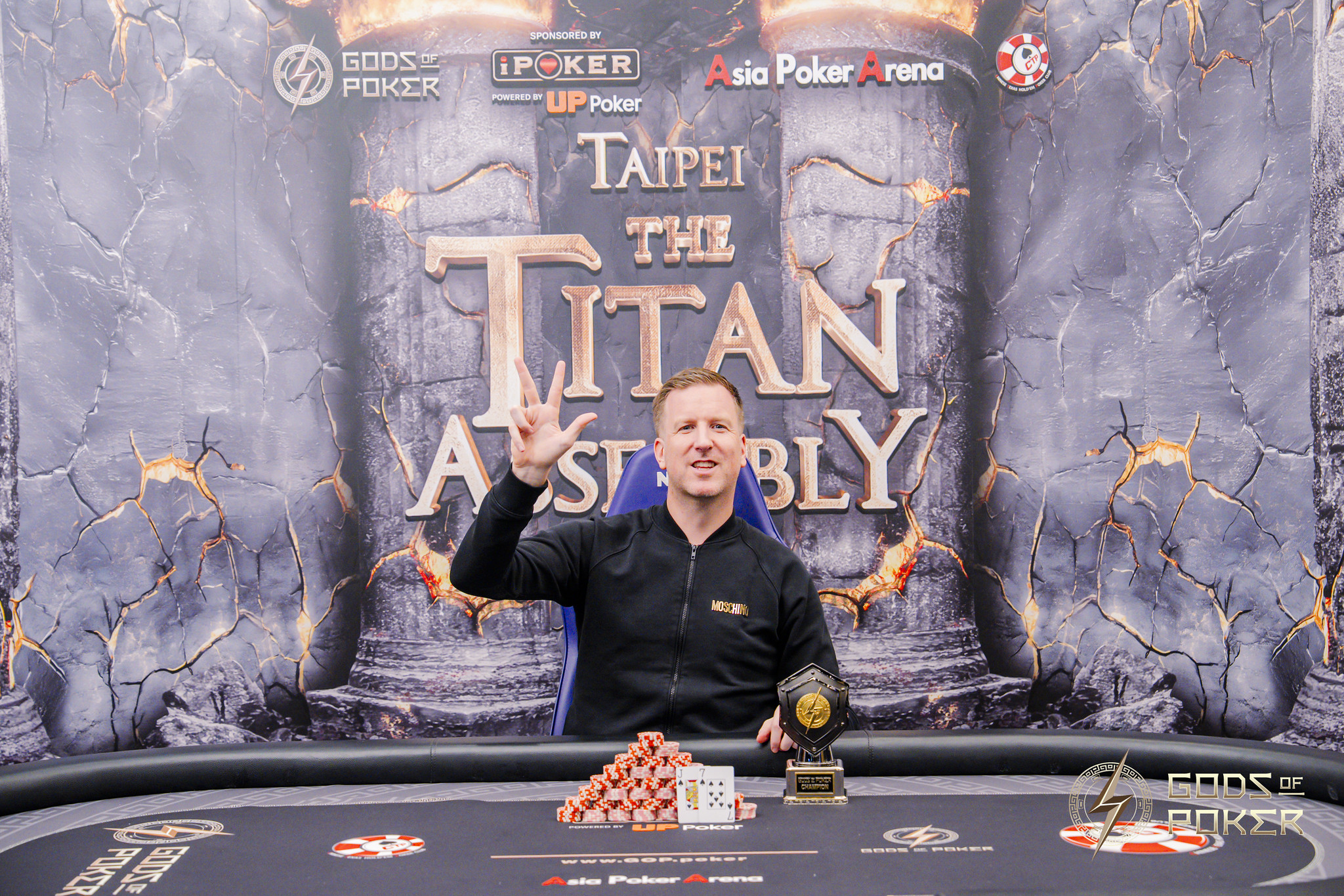 Man celebrating with a trophy and poker chips after winning the Taipei The Titan Assembly tournament.