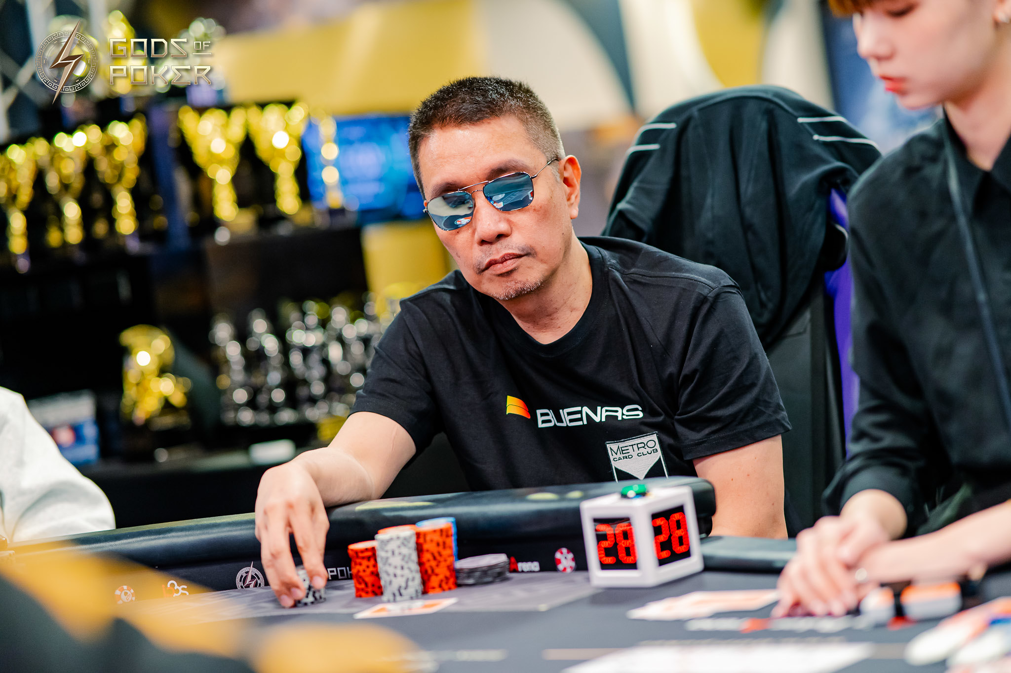 Poker player in sunglasses concentrates during a game, chips on table.